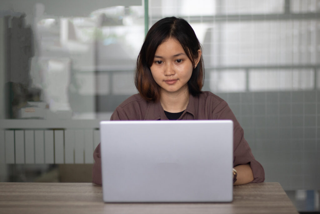 focused-asian-woman-using-laptop-office-day